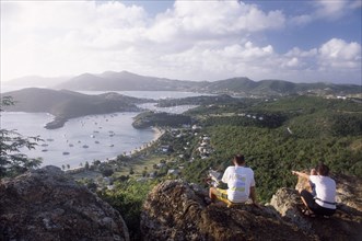 WEST INDIES, Antigua, General, Couple sitting on rocks on hillside above Ordnance bay on the right