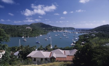 WEST INDIES, Antigua, Ordnance Bay, View over house rooftops towards bay with moored yachts and