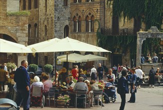 ITALY, Tuscany, San Gimignano, Street scene with people sitting at outside tables of busy cafe with