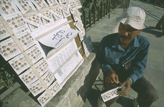 SYRIA, Damascus, Local street vendor selling lottery tickets on the side of a path.