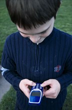 COMMUNICATIONS, Telephones, Mobile, Close up of a boy holding a blue mobile phone with thumbs on