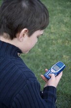 COMMUNICATIONS, Telephones, Mobile, View over the shoulder of a boy holding a blue mobile phone