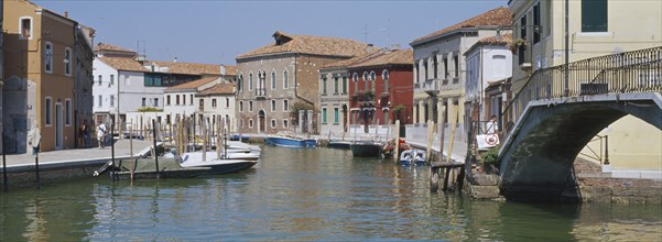 ITALY, Veneto, Venice, Murano Island.  View along canal lined by traditional houses with boats