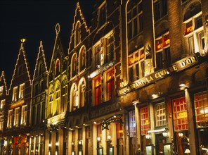 BELGIUM, West Flanders, Bruges, Grand Market. Shops and restaurant facades illuminated at night.