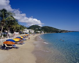 WEST INDIES, US Virgin Islands, St Thomas, Frenchman Bay.  View along sandy beach with row of sun