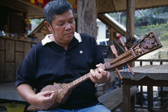 THAILAND, North, Chiang Mai, Man playing traditional stringed instrument