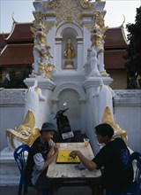 THAILAND, North, Chiang Mai, Wat Mahawan temple with two boys playing go on the pavement below