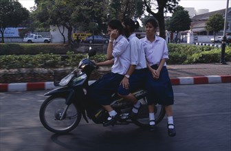 THAILAND, North, Chiang Mai, Speeding moped carrying three girls dressed in uniform with the driver