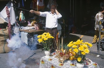 THAILAND, North, Chiang Mai, "Chinese New Year.  Man at roadside stall holding his ears as he sets