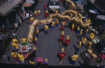 20021755 THAILAND North Chiang Mai Chinese New Year.  View looking down on Dragon Dance and watching crowds under striped awning and sun umbrellas lining road.