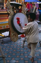 THAILAND, North, Chiang Mai, Wat Chettawan on Tha Phae Road.  Young boy playing drum suspended on
