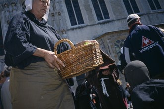 BELGIUM, West Flanders, Bruges, Street performer carrying basket during outdoor play in Burg Square