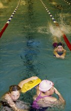 20022539 SPORT Swimming Swimming Pool Three girls at swimming club practice in pool with floats.