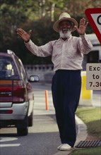 BERMUDA, Hamilton, Local character Johnny Barnes at roadside laughing and throwing his hands up in