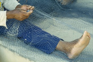 WEST INDIES, St Lucia, Anse La Raye, "Fishermen repairing nets on the beach, view of bare feet,
