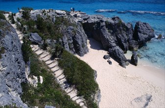 BERMUDA, Warwick, Astwood Park, Two people standing on cliff top above empty sandy beach with steps