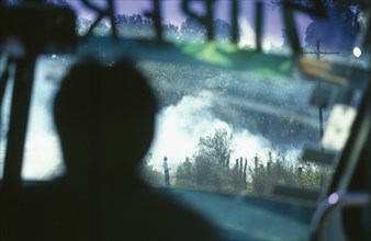 MEXICO, Near Angangueo, Burning stubble as seen from inside a Super Bus with man silhouetted.