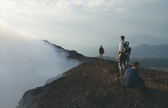 GUATEMALA, Pacaya Volcano, People standing on the rim of the smoking crater.