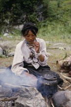CHINA, Tibet, Tibetan woman boiling tea on the roadside.