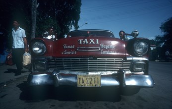 CUBA, Granma Province, Bayamo, Red 1950 s Cadillac taxi parked by the kerb