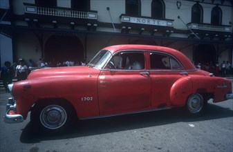 CUBA, Ciego de Avila, Moron, Red 1950 s car being driven in the street
