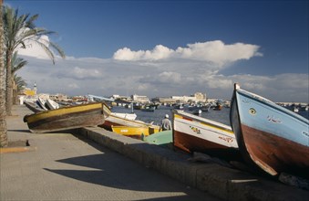 EGYPT, Alexandria, View of fishing boats pulled ashore with view of the harbour and Fort Qaitbey