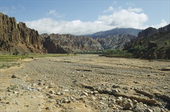 CHINA, Qinghai , Dry gravel bed of seasonal river in canyon surrounded by high altitude cliffs