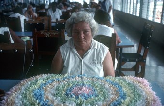 CUBA, Institue of Psychiatry, Female inmate sitting at a table in front of floral design