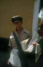 CUBA, Havana, Newspaper vendor standing in the street