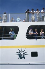 USA, New York, New York City, Circle Line ferry to Liberty Island with passengers leaning over the