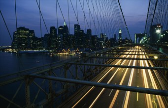 USA, New York, New York City, Brooklyn Bridge with speeding traffic headlights at night