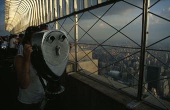 USA, New York , New York City, Woman looking through a chrome viewer at the top of the Empire State