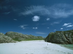 SCOTLAND, Strathclyde, Isle of Mull, White Sand Beach with large moss covered bolders and a woman