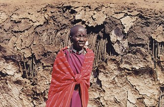 KENYA, Tribal People, Maasai woman in front of mud and straw hut