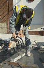 ARCHITECTURE, Construction, Workman cutting pavement slabs with angle grinder