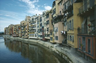 SPAIN, Gerona, View along riverbank apartments with washing hanging from balconies