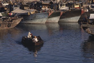 CHINA, Hainan Island , Sanya, People in a small motor boat passing in front of fishing boats moored