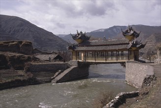 CHINA, Sichuan Province, Songpan, Chinese bridge with pagoda style roof over river in mountain