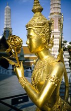 THAILAND, Bangkok, Wat Phra Kaew, Or Royal Palace. Golden temple statue of a figure holding a