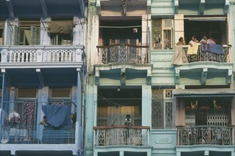 MYANMAR, Yangon, Building detail of balconies with hanging washing and people standing