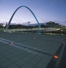 ENGLAND, Tyne and wear, Gateshead, The new Millennium Footbridge illuminated at dusk with city