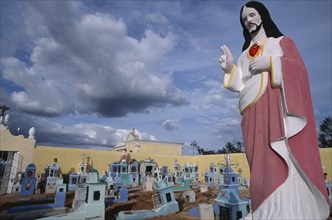 MEXICO, Yucatan, Hoctun, Cemetery with painted religious statue in the foreground and graves