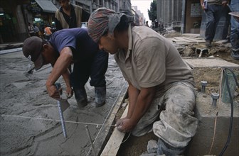 MEXICO, Mexico City, Construction workers laying concrete on building site.