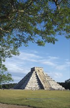 MEXICO, Yucatan, Chichen Itza, "El Castillo, angled view of facade partly framed by tree branches