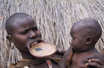 ETHIOPIA, Western Highlands, Children, Surma woman with lip plate holding baby.