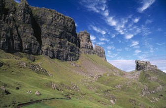 SCOTLAND, Isle of Skye, North, Quiraing Escarpment Mountains with walker on lower slopes.