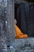 CAMBODIA, Angkor, The Bayon.  Portrait of Buddhist monk framed in temple window.
