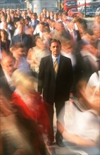 BUSINESS, Commuters, City businessman in suit standing motionless surrounded by crowds in blurred