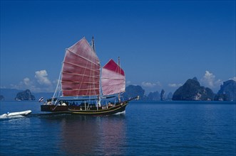 THAILAND,  , Phuket, Tourist excursion on Chinese Junk with pink sails reflected in deep blue water