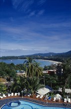 THAILAND, Phuket , Kata Beach, View over hotel swimming pool with tourists on sun loungers beside